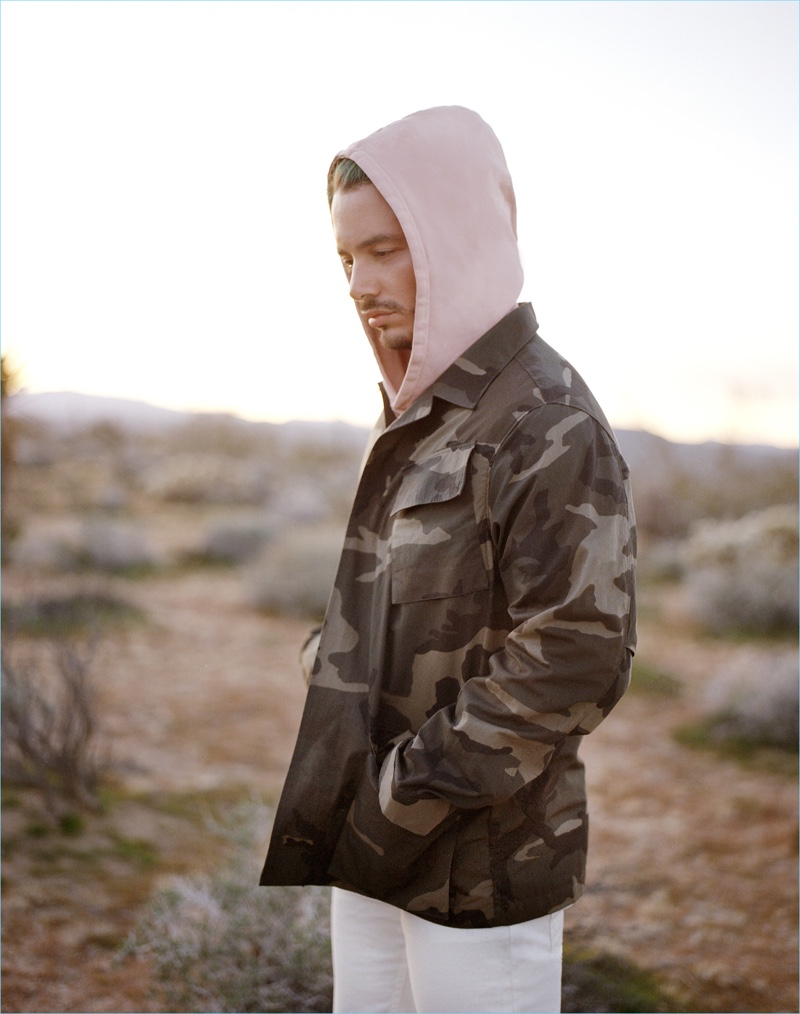 Music artist J Balvin rocks an Ovadia & Sons camouflage print field jacket $485, washed rose Type-01 hoodie $195, and white slim-fit distressed jeans $250.