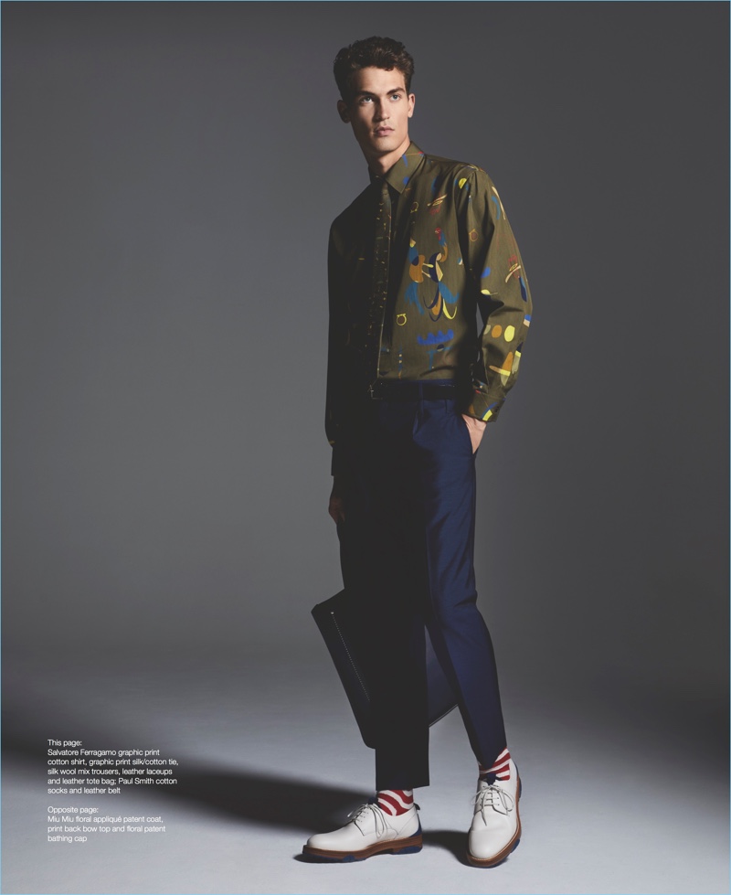 Front and center, Jason Anthony wears a Salvatore Ferragamo graphic print shirt with a tie, trousers, sneakers, and tote. Jason also dons Paul Smith socks with a leather belt.
