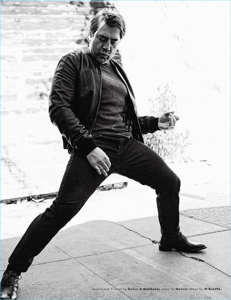 Striking a dance move, Javier Bardem dons a t-shirt and jacket by Dolce & Gabbana with Gucci jeans and O'Keeffe shoes.