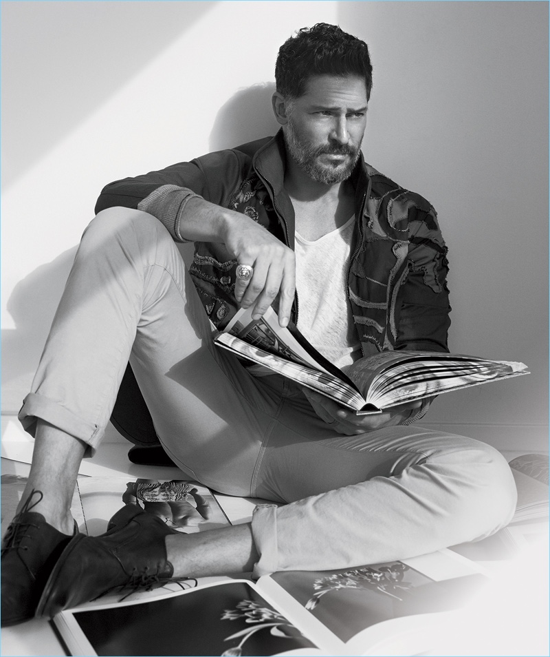 Flipping through art books, Joe Manganiello wears a camouflage Valentino jacket with a t-shirt and shoes by John Varvatos. Manganiello also sports Bottega Veneta jeans.