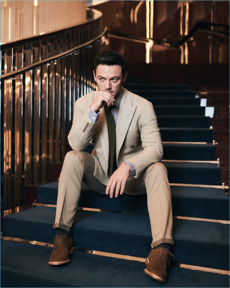 Stealing a moment, Luke Evans sports a shirt and double-breasted jacket by Ralph Lauren Purple Label. Evans also wears a New & Lingwood tie, Hackett London chinos, and Grenson shoes.