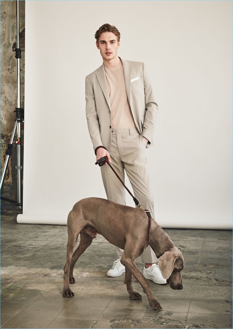 Tommy Marr goes semi-casual in a suit and sweater. The British model wears a Mango Man slim-fit suit blazer $139.99, linen silk-blend sweater $39.99, trousers $69.99, and lace-up leather sneakers $69.99.