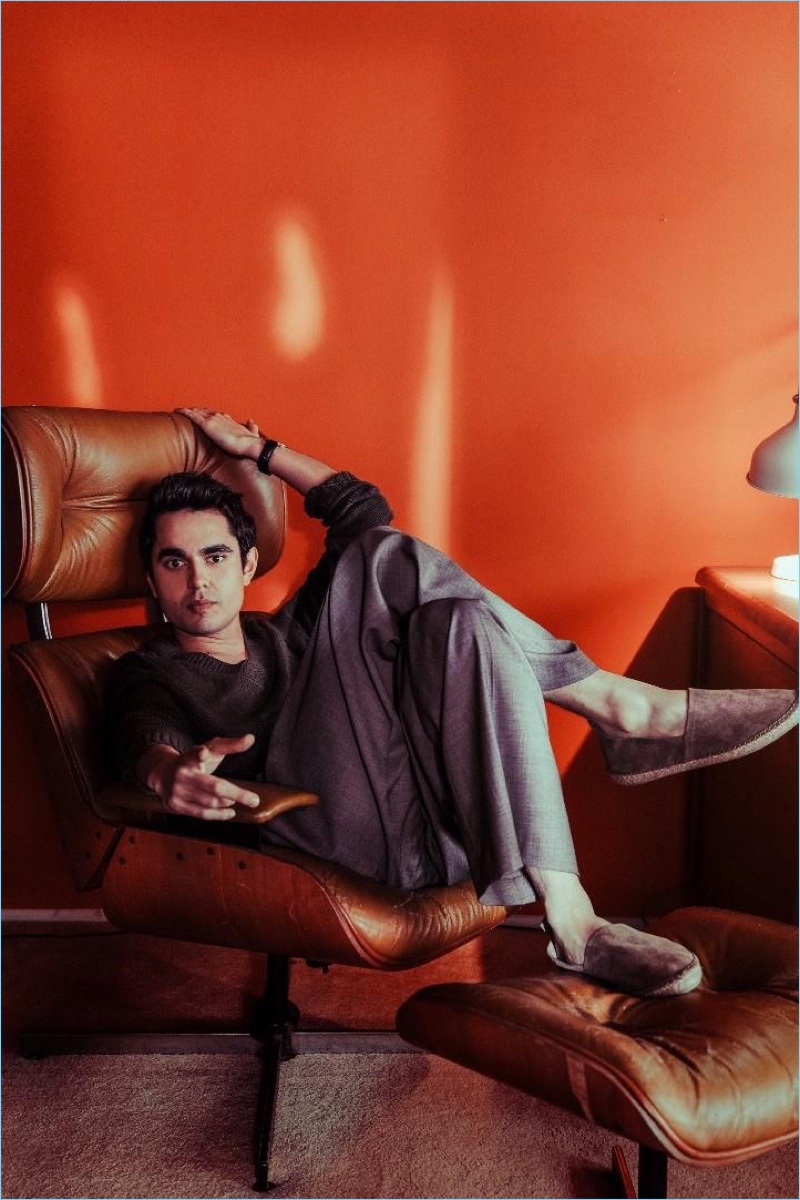 Relaxing, Max Minghella sports an Etro sweater, Versace trousers, and Brunello Cucinelli espadrilles.