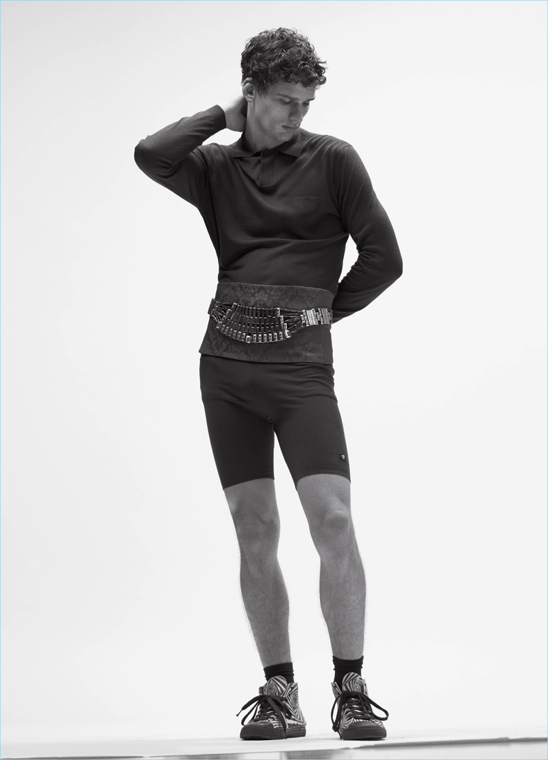 Appearing in an editorial for VMAN, Simon Nessman wears a Versace top and shorts with a Balenciaga cummerbund.