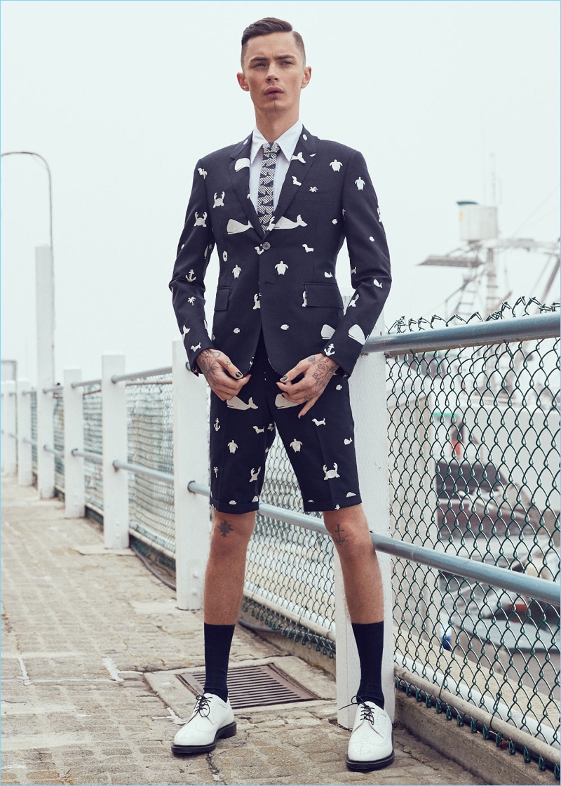 Making a nautical print statement, Simon Kotyk wears a Thom Browne tonal multi icon fun mix blazer $2,900, classic short-sleeve button-down with ribbon placket $425, and fun mix shorts $1,150. Simon also dons Thom Browne contrast longwing leather brogues $1,250 and a whale houndstooth tie $210.