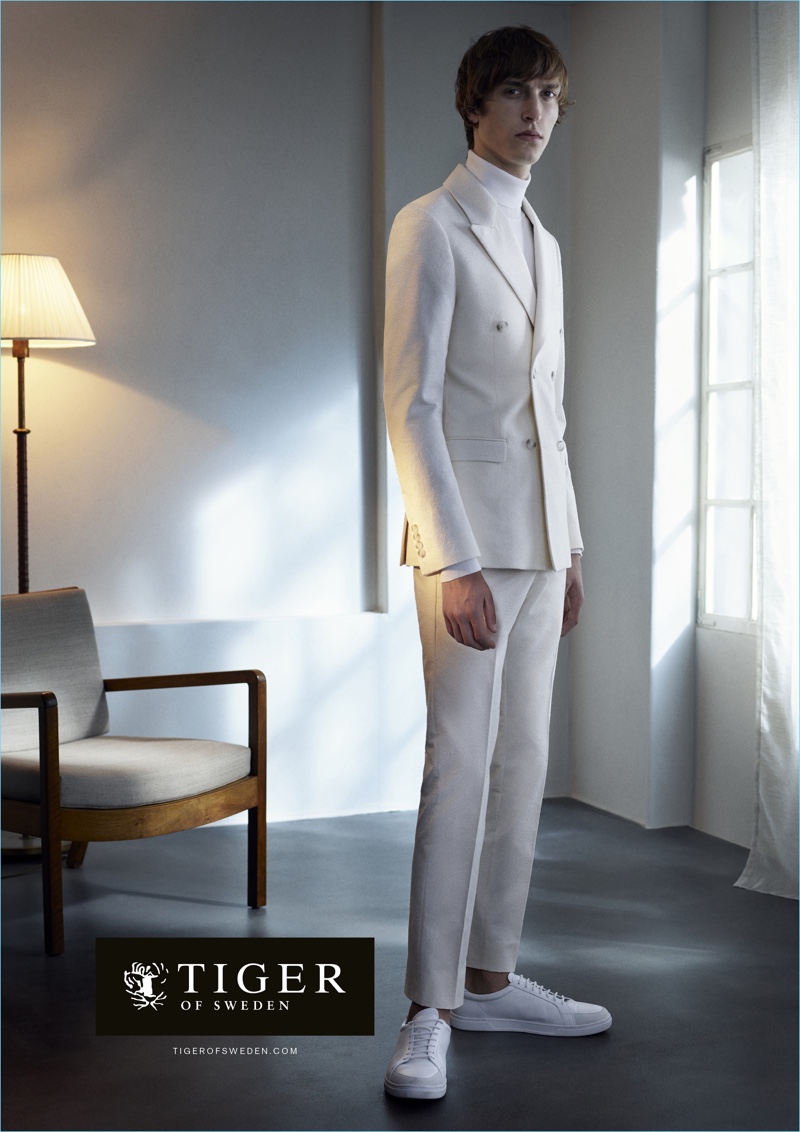 A vision in white, Tim Dibble dons a double-breasted suit and turtleneck with sneakers for Tiger of Sweden's spring-summer 2017 campaign.