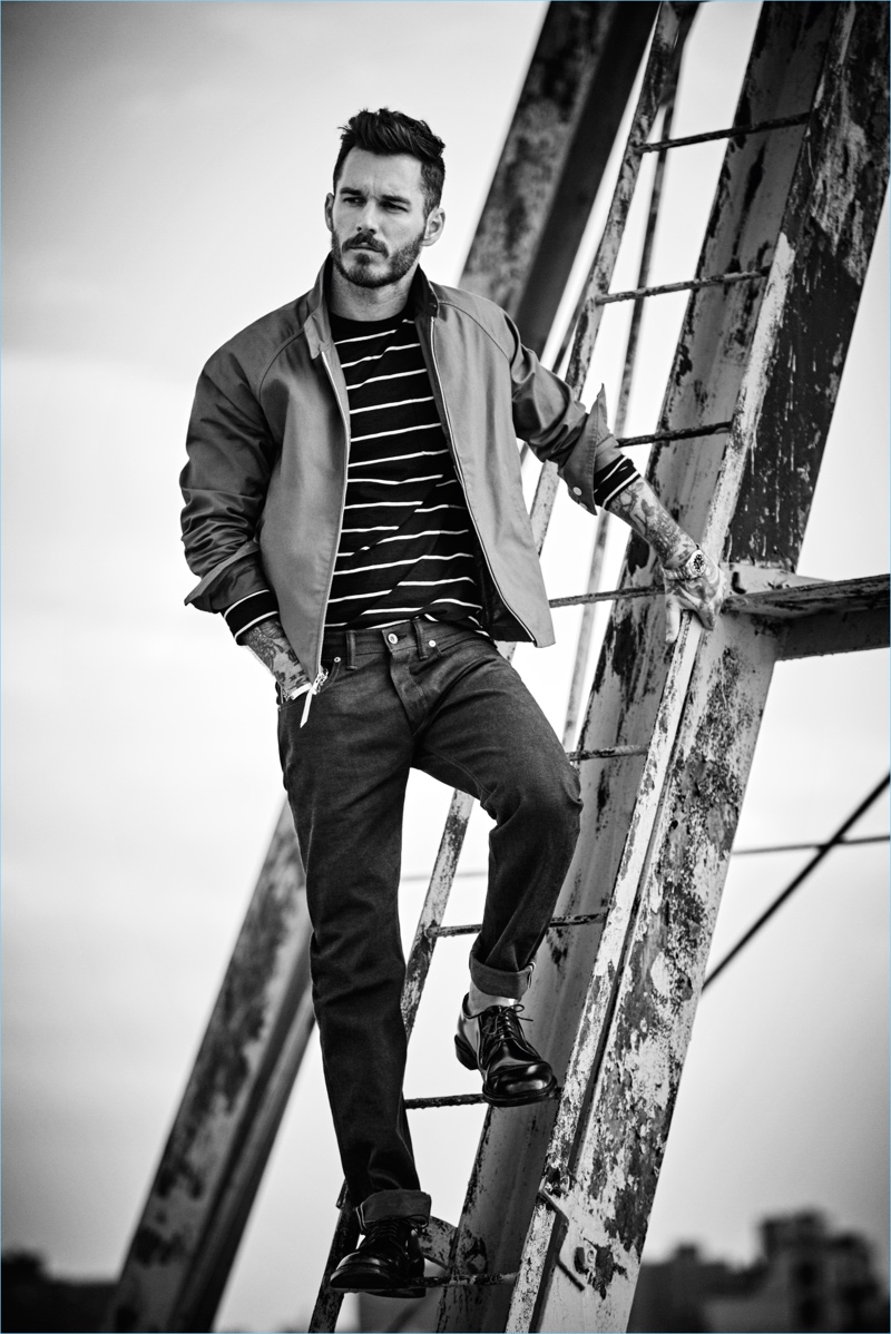 Posing on a ladder, David Alexander Flinn wears a Todd Snyder long-sleeve striped tee $98, Harrington jacket $328, and selvedge denim jeans $198.