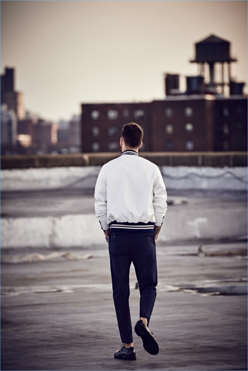 Walking away from the camera, David Alexander Flinn wears a white Todd Snyder + Champion bomber jacket $348 and Japanese selvedge chino officer pant $198.