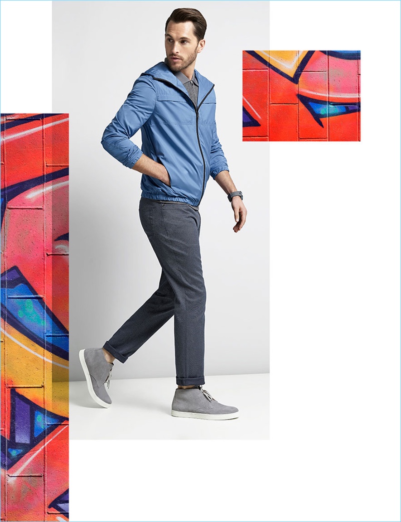 Going casual, Jake Davies wears a blue Vince Camuto mesh-hood windbreaker $175, slim-fit mesh polo $95, dotted chinos $98, and grey chukka sneakers $195.