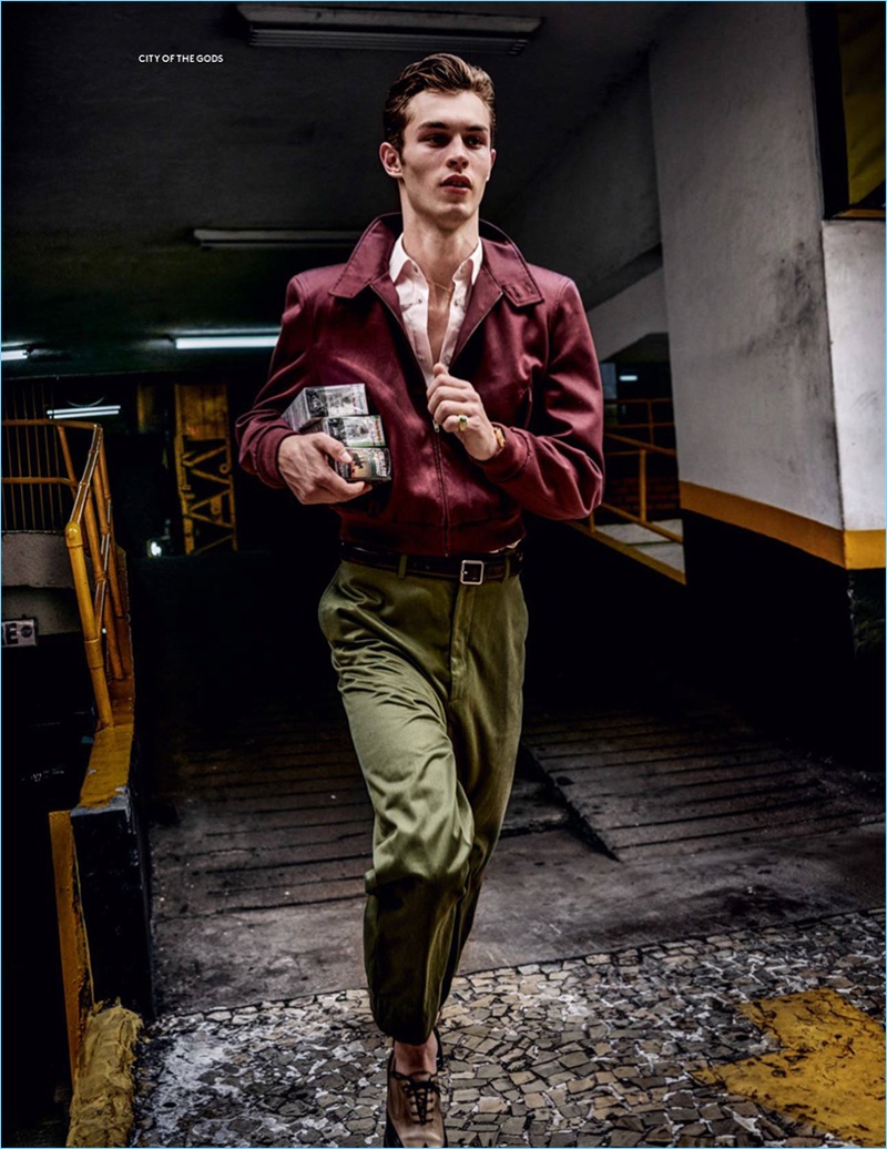 On the move, Kit Butler wears a bomber jacket, shirt, and chinos by Balenciaga with Salvatore Ferragamo shoes.