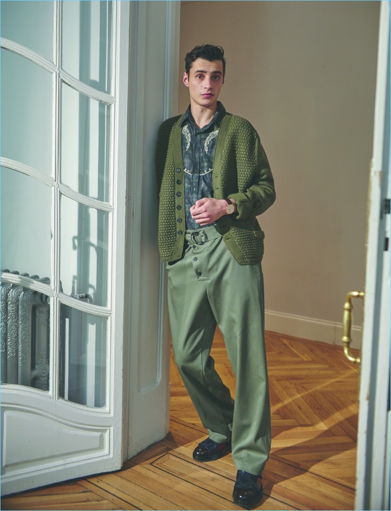 A smart vision, Adrien Sahores wears a green Loewe cardigan sweater with a Missoni shirt. The leading model also rocks Emporio Armani trousers and Salvatore Ferragamo shoes with a Tissot watch.