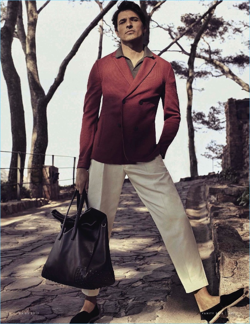Making a sartorial statement, Andres Velencoso wears a double-breasted blazer and polo by Falconeri. The Spanish model also sports Barba Napoli trousers, Giuseppe Zanotti espadrilles, and a leather Tod's bag.