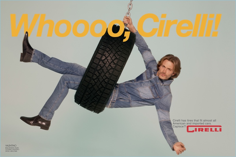 Swinging in a tire, Brad Kroenig wears a denim look by Valentino with Carvil Paris shoes.