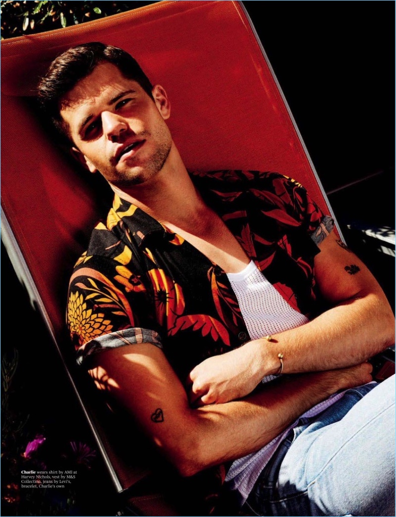 Lounging, Charlie Carver sports an AMI shirt with a M65 Collection tank, and Levi's denim jeans.