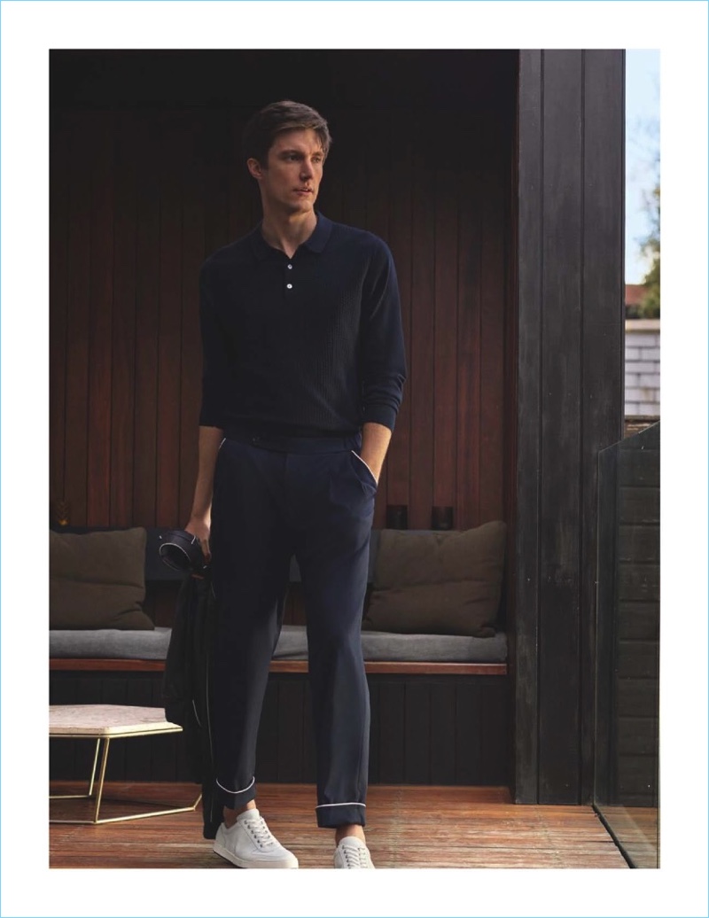 Sporting a navy look, Charlie Timms wears a Massimo Dutti knit polo and trousers detailed with white piping. The British model also rocks white sneakers.