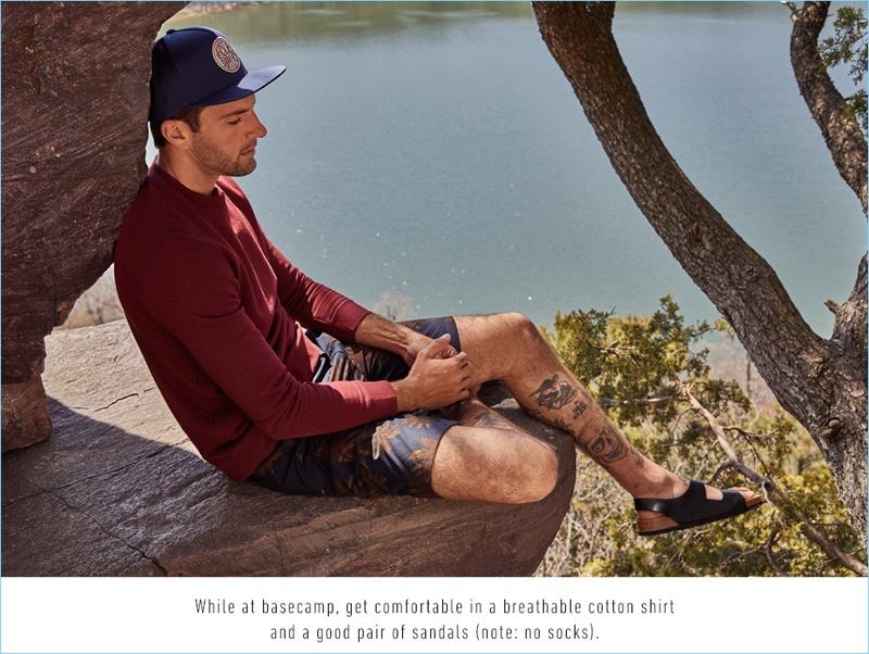 Relaxing, Rafael Lazzini wears a Naked & Famous sweatshirt $115, Vince leaf print chino shorts $185, Birkenstock sandals $135, and Herschel Supply Co. cap $30.