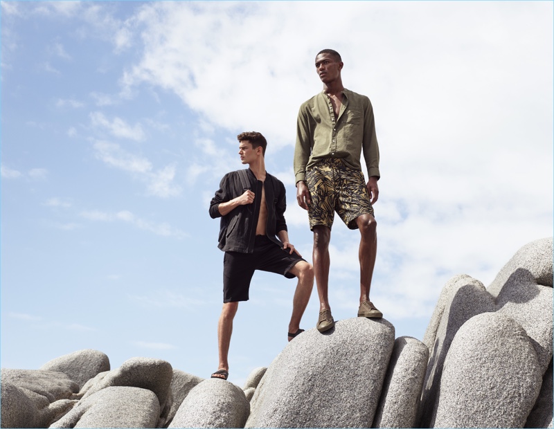 Left to Right: Arthur Gosse wears a linen bomber jacket $59.99 with knee-length cotton shorts $24.99, and sandals $24.99. Hamid Onifade sports a collarless shirt $34.99 and patterned knee-length shorts $24.99 with sneakers.