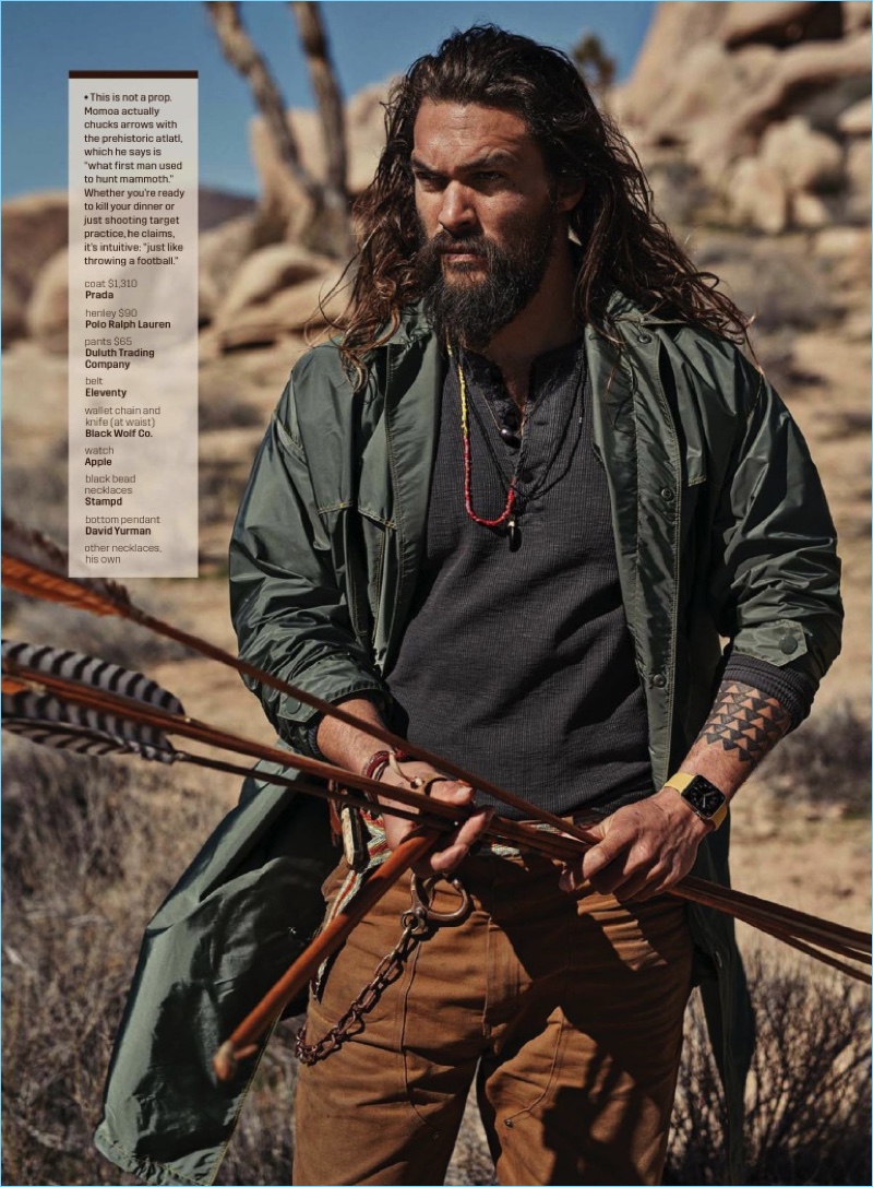 Starring in a GQ photo shoot, Jason Momoa wears a Prada coat with a POLO Ralph Lauren henley, Duluth Trading Company pants, and an Eleventy Belt.
