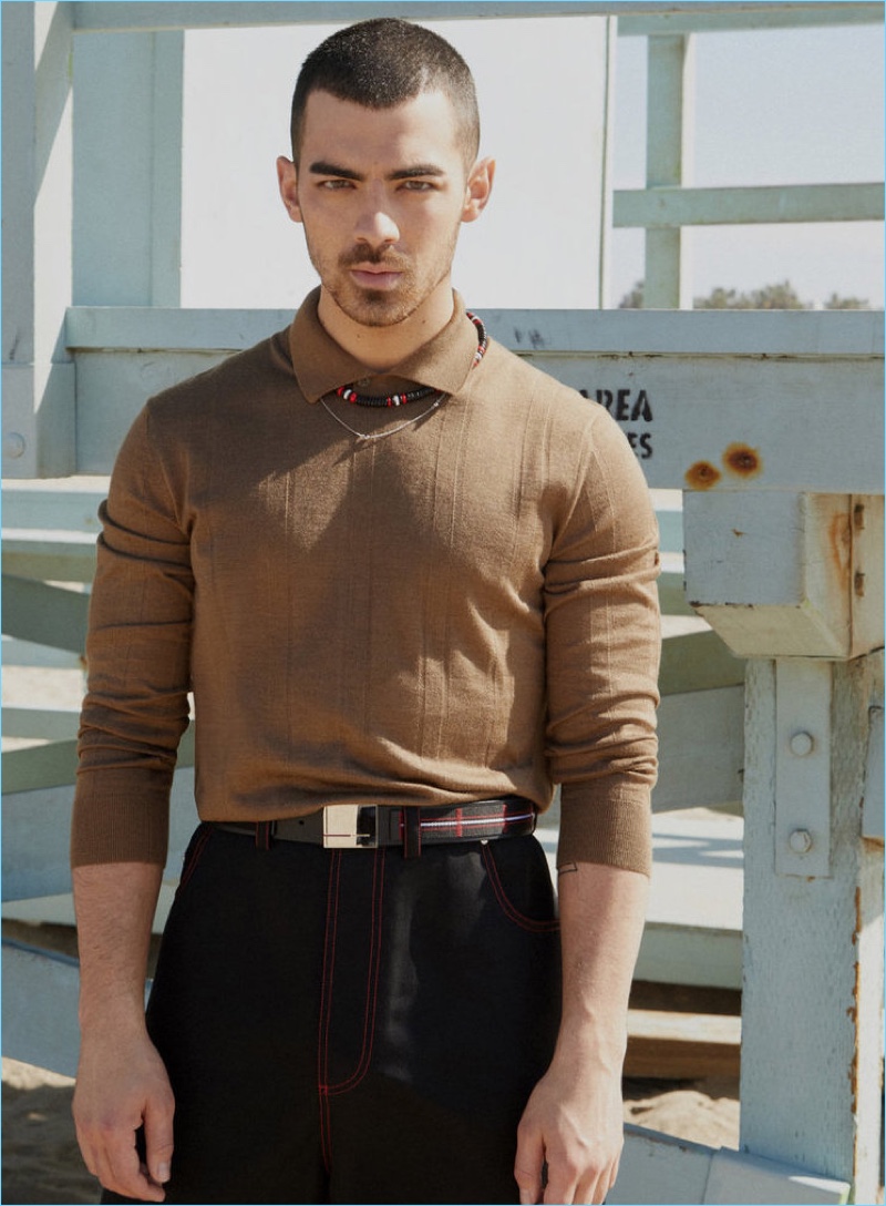 Embracing a brown and black color palette, Joe Jonas wears an Ermenegildo Zegna Couture polo. Jonas also sports jeans, a belt, and necklace by Dior Homme.