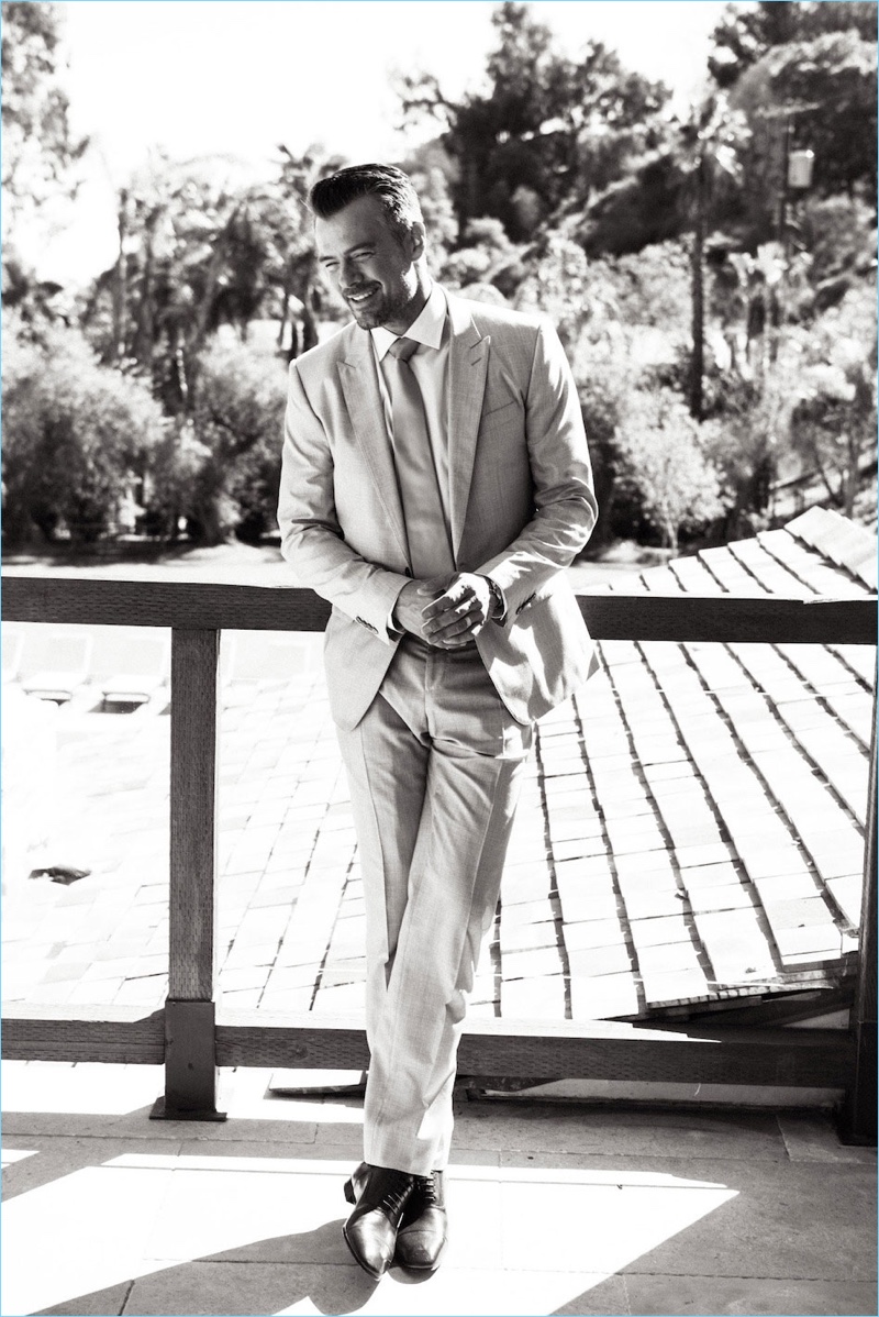 Charming in a black and white photo, Josh Duhamel dons a Dolce & Gabbana suit and tie. He also wears a John Varvatos shirt and Christian Louboutin dress shoes.