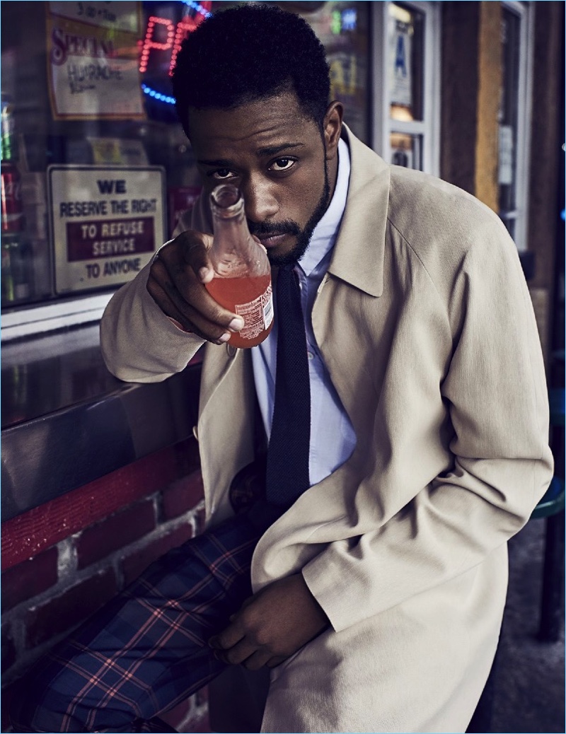 Enjoying a drink, Lakeith Stanfield wears a Bottega Veneta coat with a shirt and tie by Margaret Howell. He also rocks Louis Vuitton check trousers.