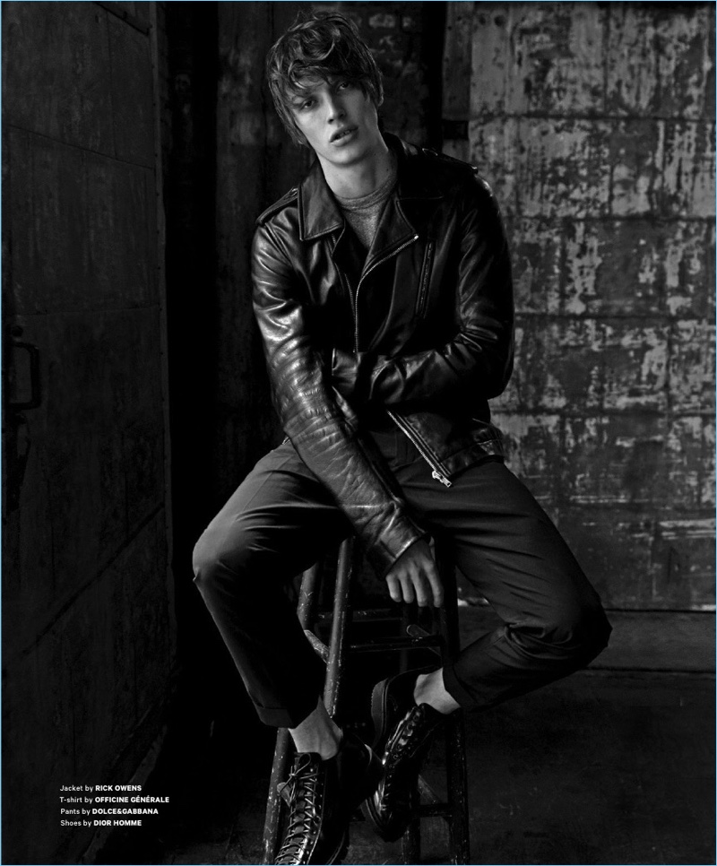 Sitting for a black and white photo, Lucas Satherley wears a Rick Owens leather biker jacket with an Officine Generale t-shirt. He also sports Dolce & Gabbana trousers with Dior Homme shoes.