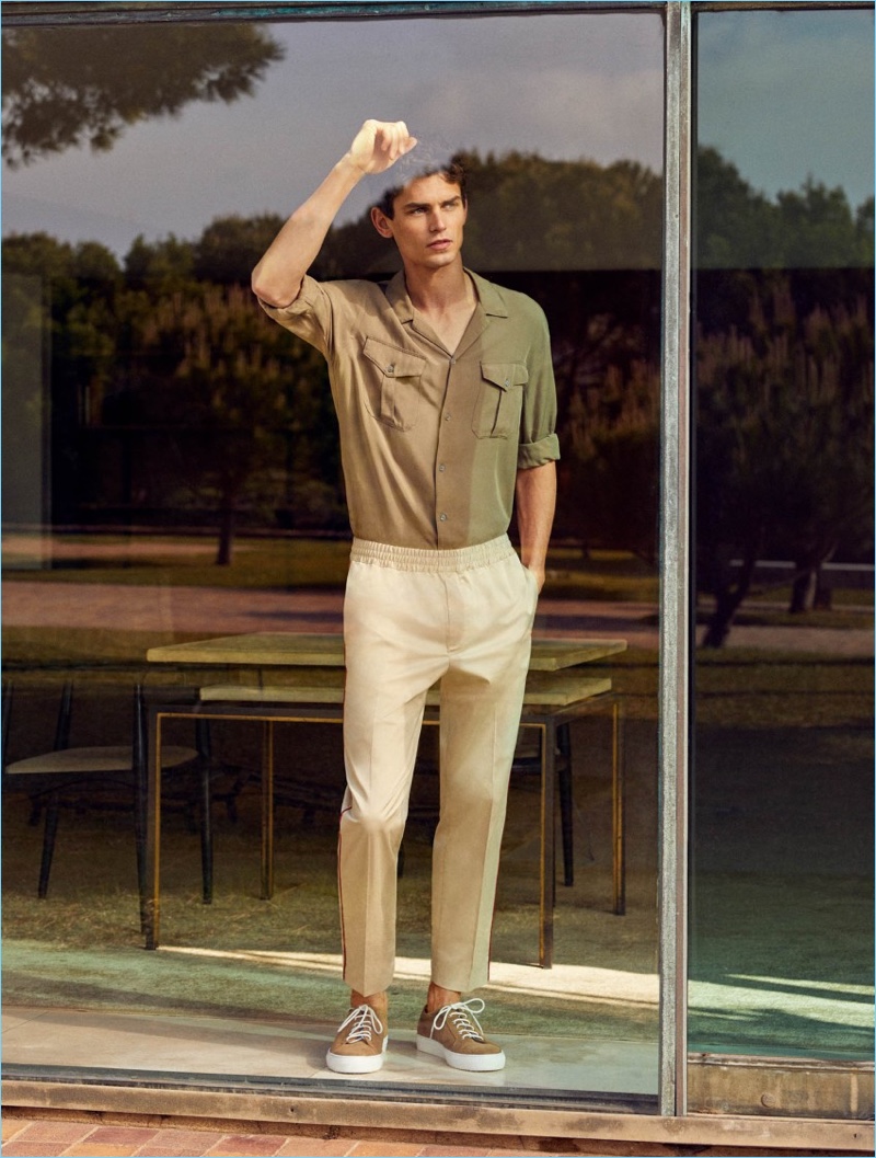 Embracing summer neutrals, Arthur Gosse sports a Mango Man chest pocket shirt $69.99, contrast trim trousers $69.99, and lace-up suede sneakers $99.99.