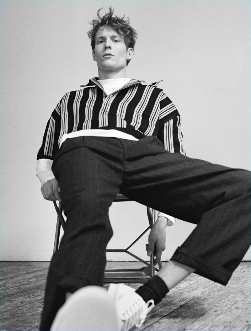 Sitting for a portrait, Felix Gesnouin sports a Raf Simons t-shirt $355 and cropped polo shirt. He also wears a Maison Margiela pinstriped trousers $412 and Stella McCartney low-top sneakers $393.