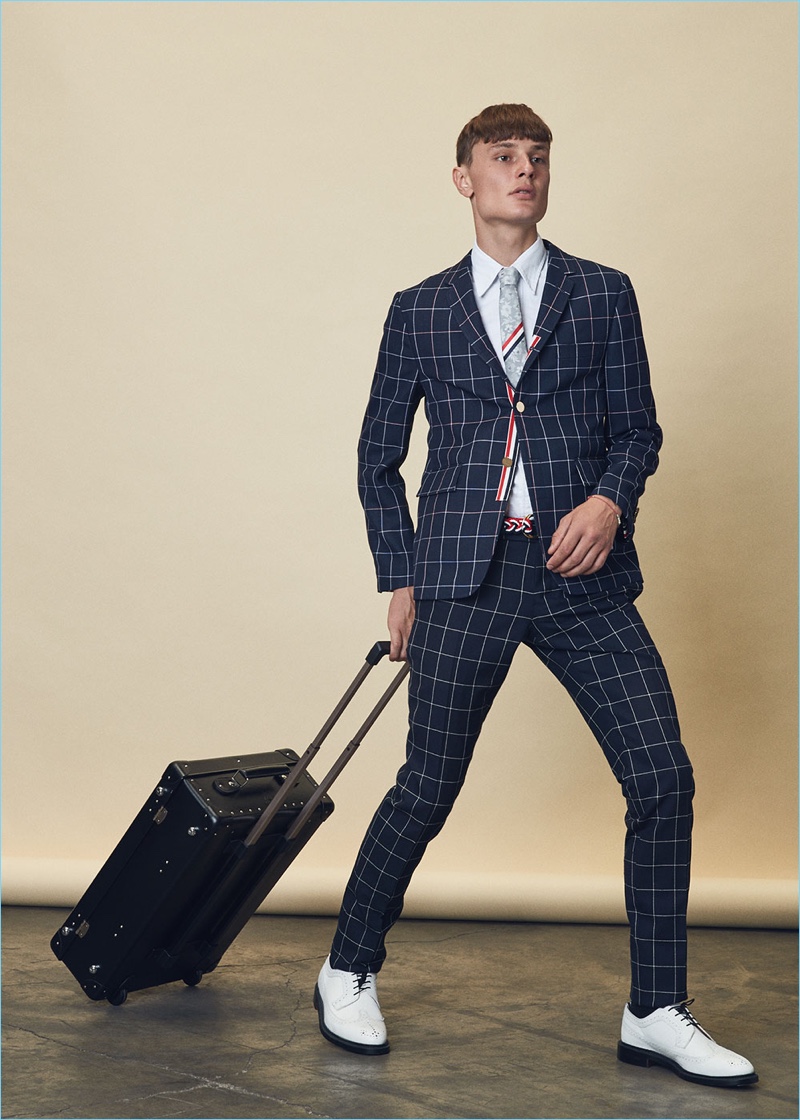 Suiting up, Vanya dons a Thom Browne windowpane blazer $1,608 and trousers $867 with a classic short-sleeve button-down $425. He also wears Thom Browne white leather brogues $1,250, a floral silk jacquard tie $240, and a nantucket braided rope D ring belt $390. Vanya carries a Globe-Trotter 21" original trolley case $1,370 as well.