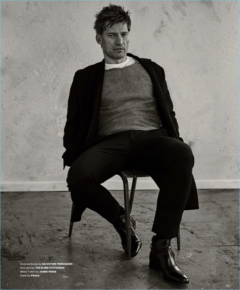 Sitting for a portrait, Nikolaj Coster-Waldau wears a coat and boots by Salvatore Ferragamo. Coster-Waldau also sports a t-shirt from The Elder Statesman, a James Perse t-shirt, and Prada trousers.