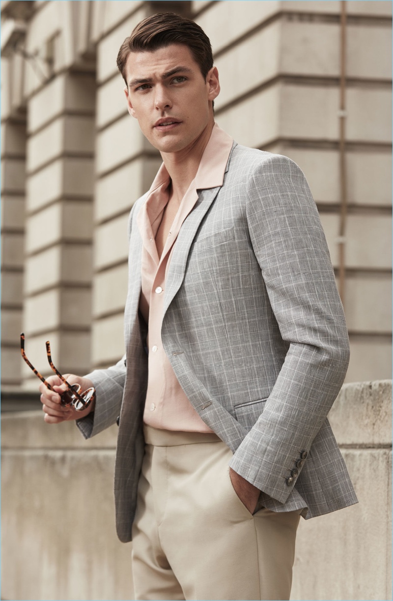 Dressing for a garden party, Filip Wolfe dons a Reiss houndstooth blazer $520 with a check Cuban collar shirt $195 and tailored trousers $275. He also sports keyhole tortoiseshell sunglasses $155.