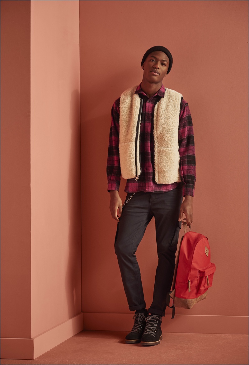 Model Hamid Onifade embraces a modern spin on rugged style with a fleece vest and plaid flannel from River Island.