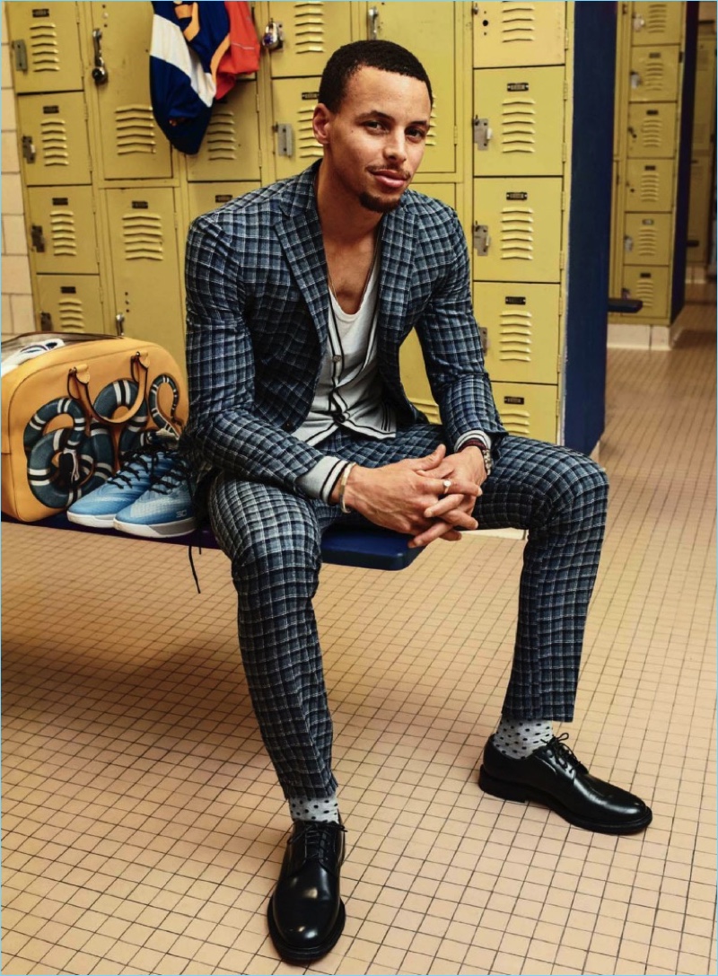 Posing for a photo in the locker room, Steph Curry dons a Boglioli suit with a Hermes cardigan and tank. Curry also wears Church's shoes, and Etiquette Clothiers socks.