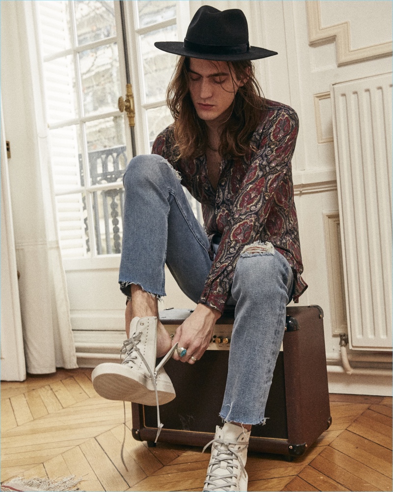 Alphonse Emery wears a paisley print shirt with cut-off denim jeans from The Kooples.