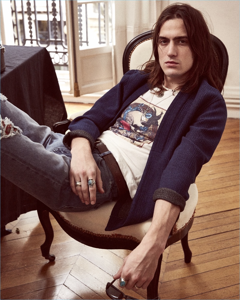 Relaxing, Alphonse Emery  sports a chic jacket with a graphic tee and ripped denim jeans from The Kooples.