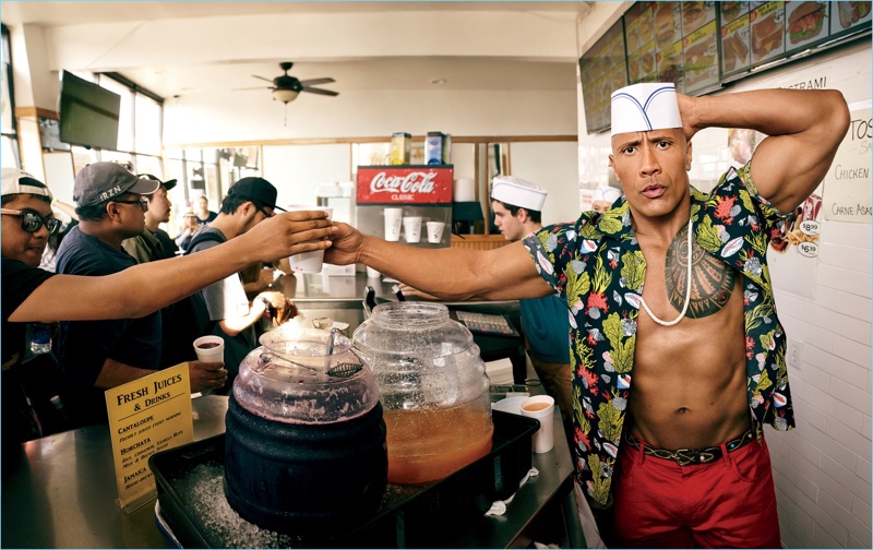 Serving juice at Thomas Hamburgers, The Rock sports a Louis Vuitton shirt with Armani Exchange pants, an Eleventy belt, and RTH necklace.