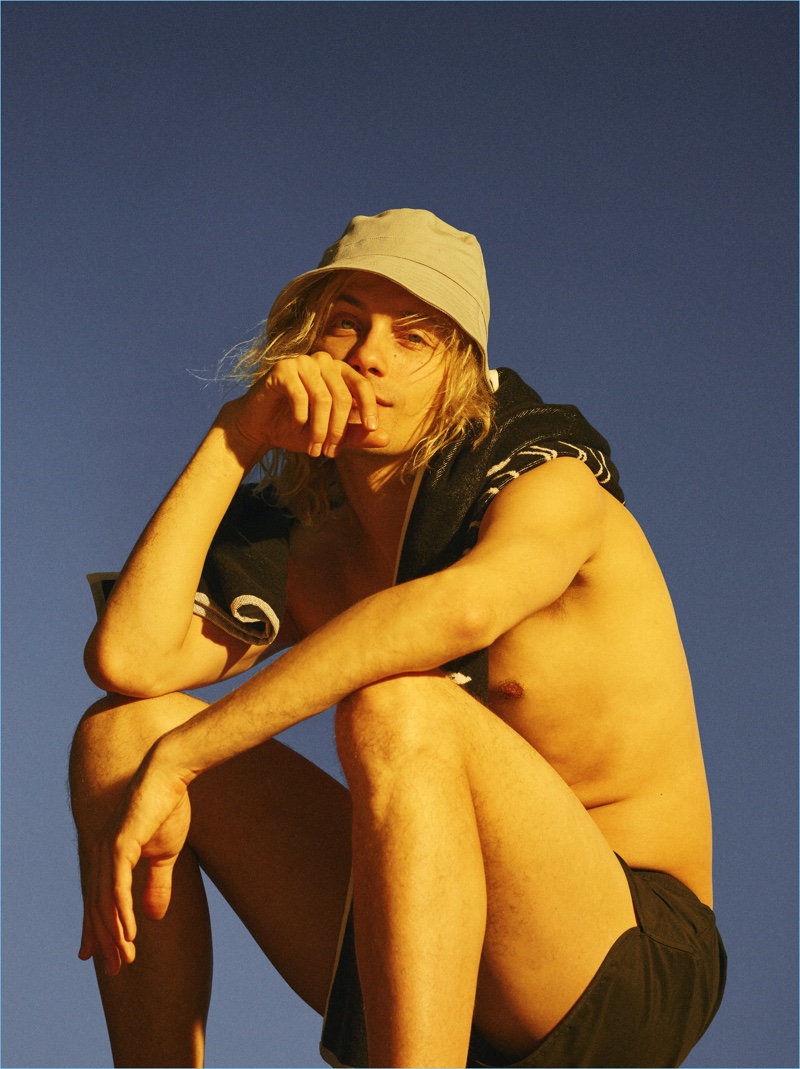 Connecting with Weekday for summer, Luke Storey relaxes in a pair of swim shorts and a bucket hat.