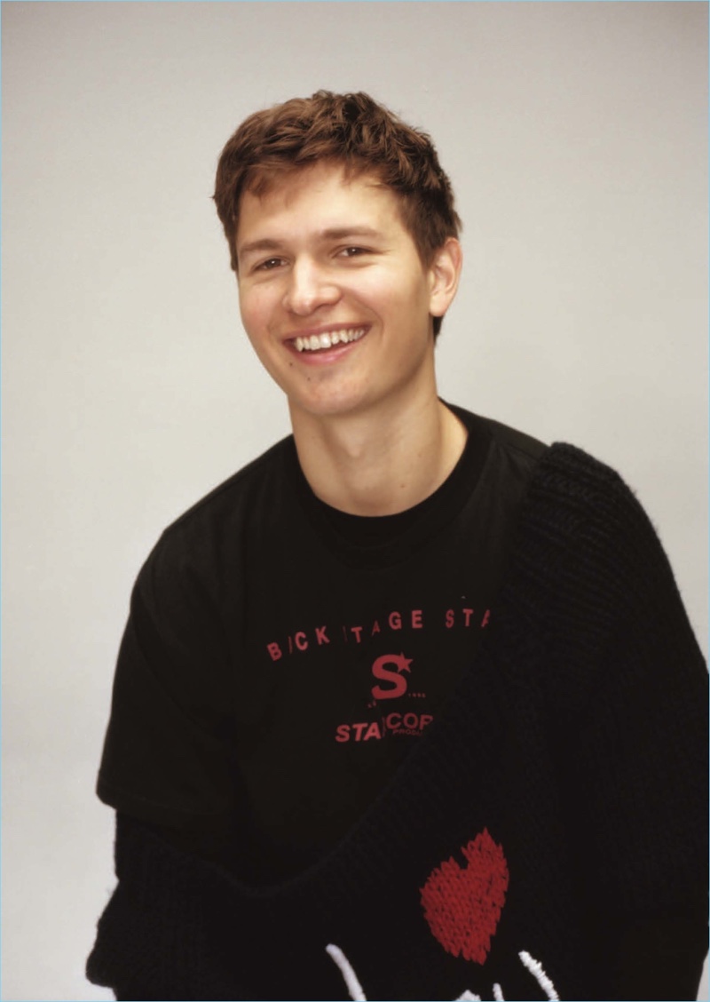 All smiles, Ansel Elgort sports a long-sleeve tee from Comfort Colors with a sweater and t-shirt by Raf Simons.