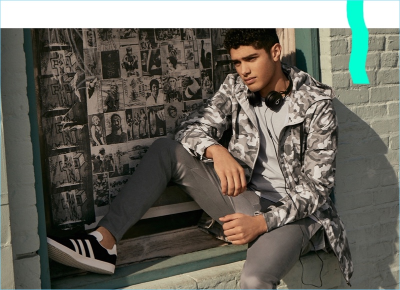 Embracing an urban appeal, Torin Verdone wears Zanerobe. He sports a Zanerobe camouflage anorak jacket $189, tee $49, and chino pants $99. Adidas Gazelle lace-up sneakers $80 complete Torin’s outfit.