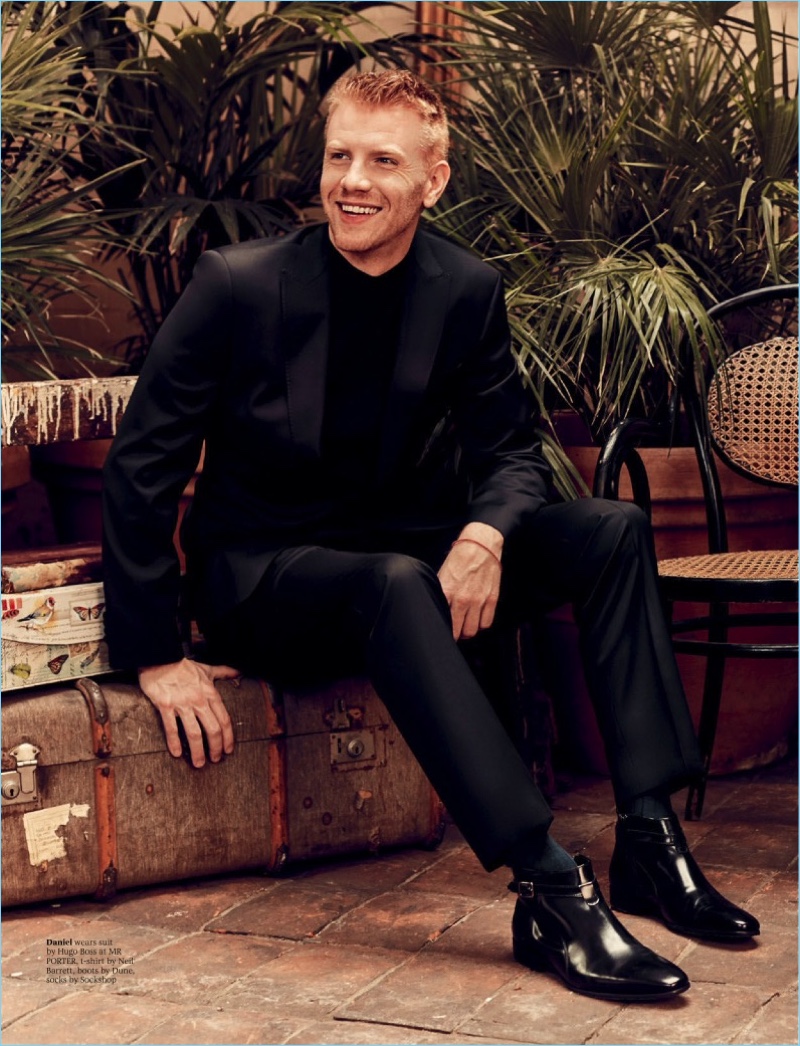 All smiles, Daniel Newman dons a Hugo Boss suit with a Neil Barrett t-shirt and Dune boots.