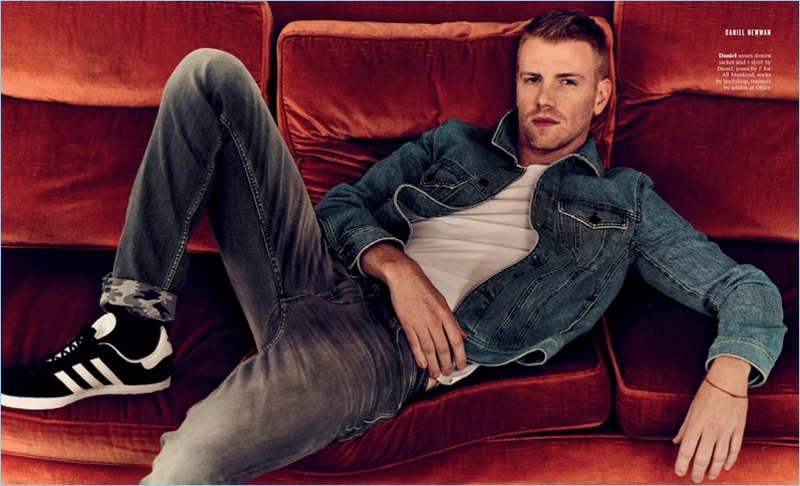 Relaxing, Daniel Newman wears a t-shirt and denim jacket by Diesel. He also sports 7 For All Mankind jeans and Adidas sneakers.