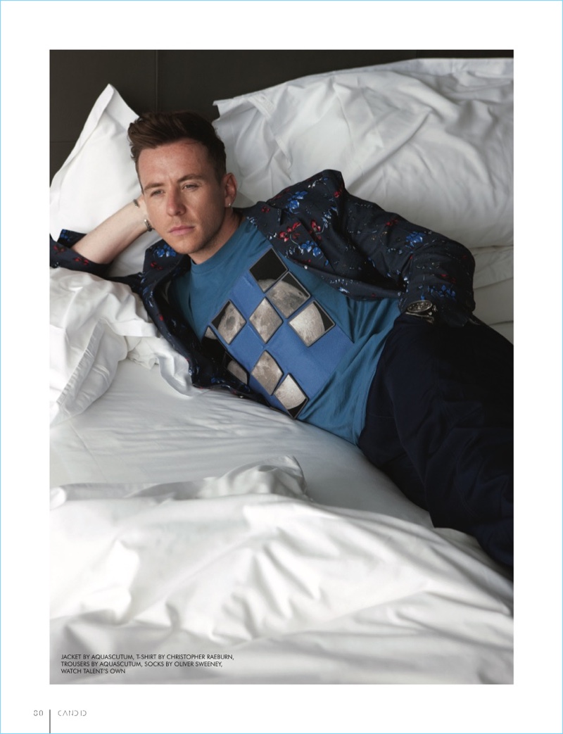 Laying in bed, Danny Jones wears an Aquascutum jacket and trousers with a Christopher Raeburn t-shirt.