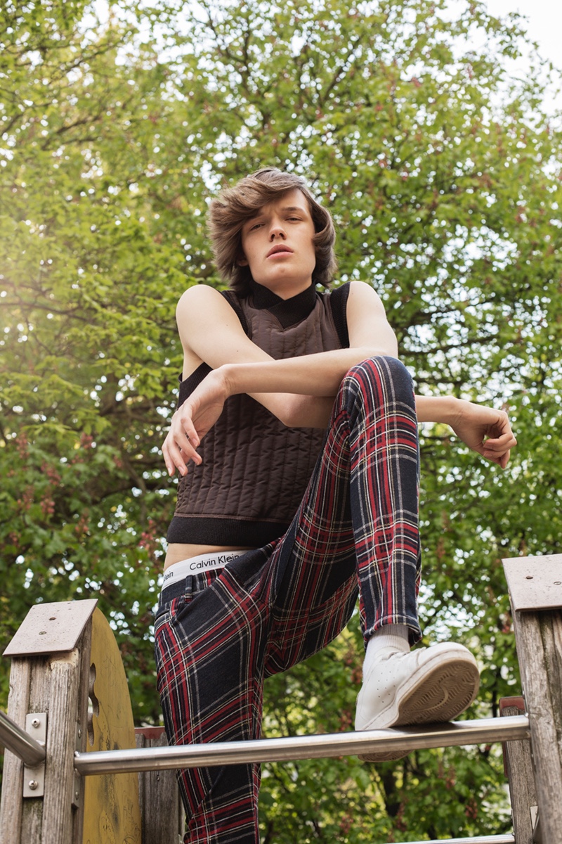 Carl wears sleeveless top Jean Paul Gaultier, check trousers Zara, underwear Calvin Klein, socks Falke, and sneakers Adidas.