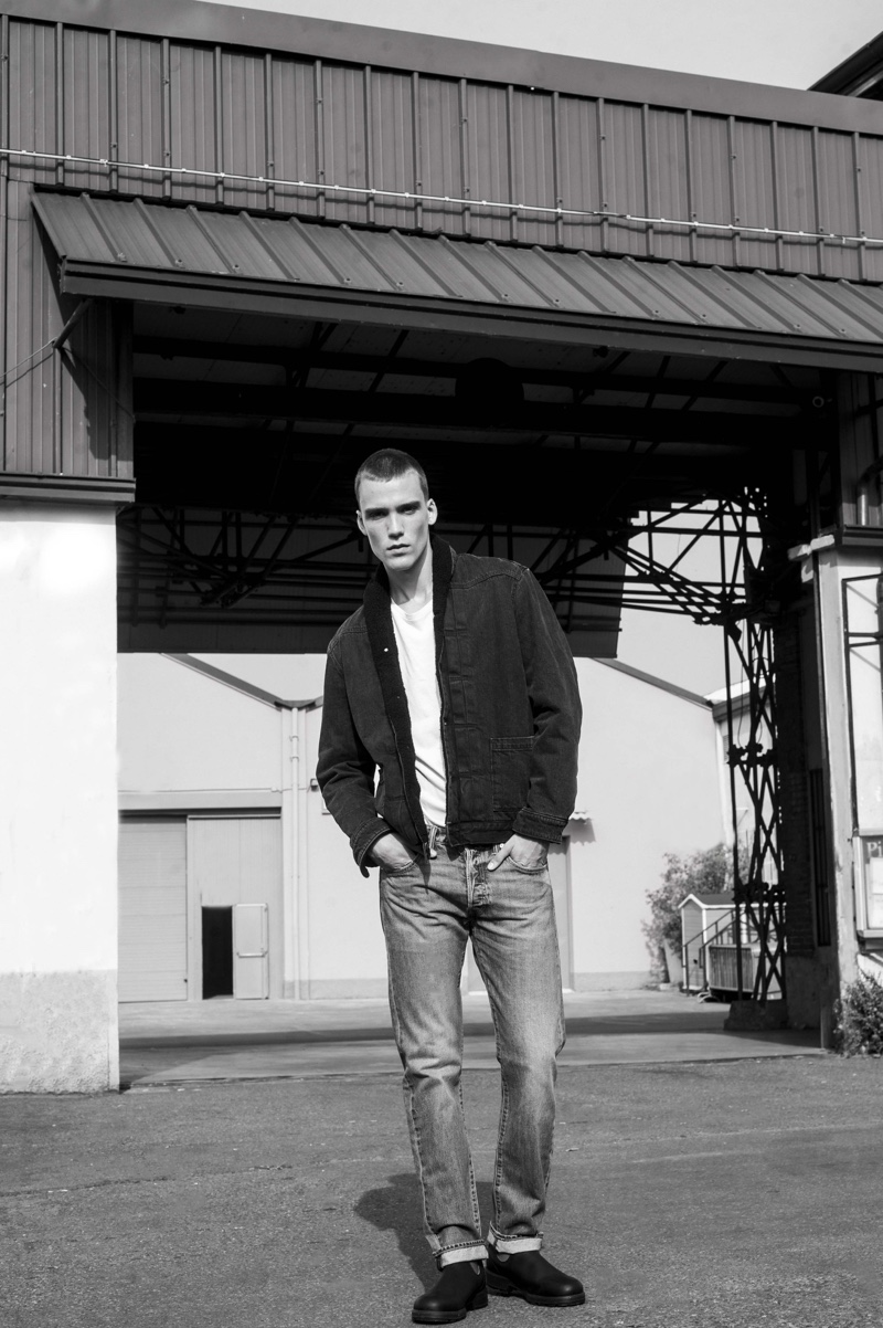 Sporting classic pieces by Levi's, Marc Lüloh wears a jacket, white tee, and distressed denim jeans.