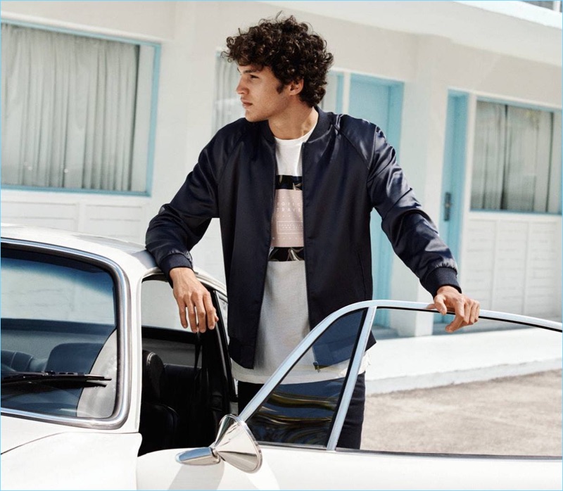 HM Men Summer 2018 Lookbook Undone Style 003 Connecting with H&M, Francisco Henriques sports an embroidered bomber jacket $59.99, graphic tee $12.99, and twill shorts $24.99.