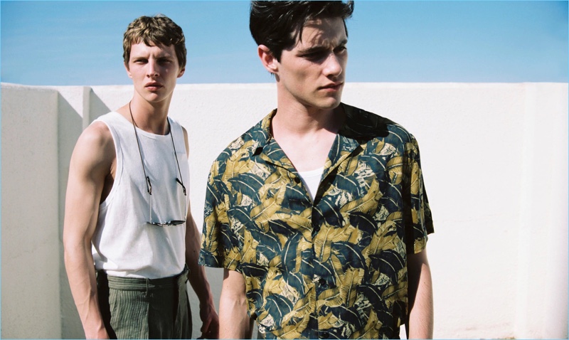 Models Luke Powell and Tim Schuhmacher come together for Mango Man's summer 2017 style edit. Pictured left to right, Tim wears a sleeveless t-shirt $12.99, trousers $69.99, and sunglasses $35.99. Meanwhile, Luke sports a tropical leaf print shirt $59.99 and sleeveless t-shirt $12.99.