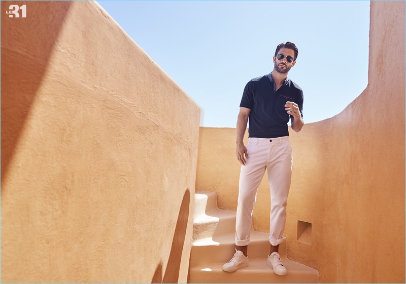 John Halls wears a cotton polo, stretch chinos, and classic aviator sunglasses by LE 31.