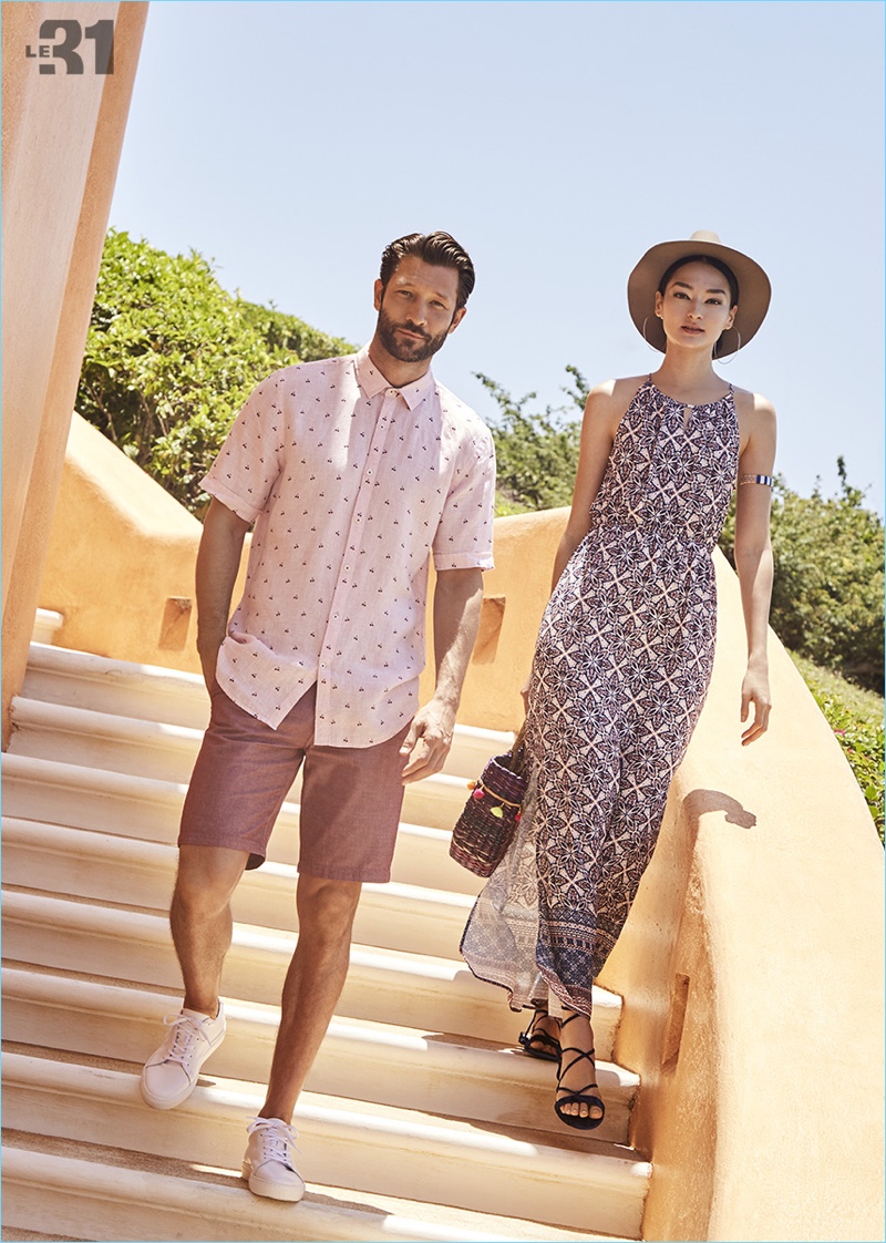 Models John Halls and Bruna Tenório couple up for Simons' summer getaway. John wears a LE 31 linen all-over print shirt and chambray Bermuda shorts with Simons leather sneakers.