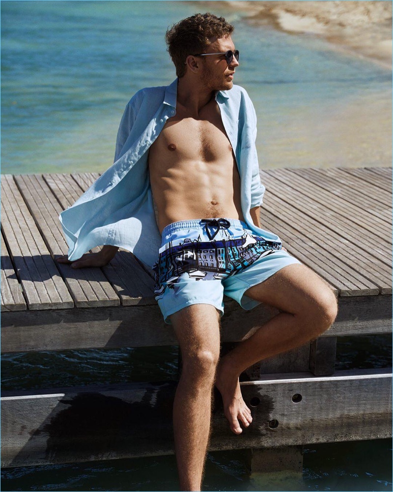Relaxing at the beach, Benjamin Eidem wears a Vilebrequin shirt and printed swim shorts.