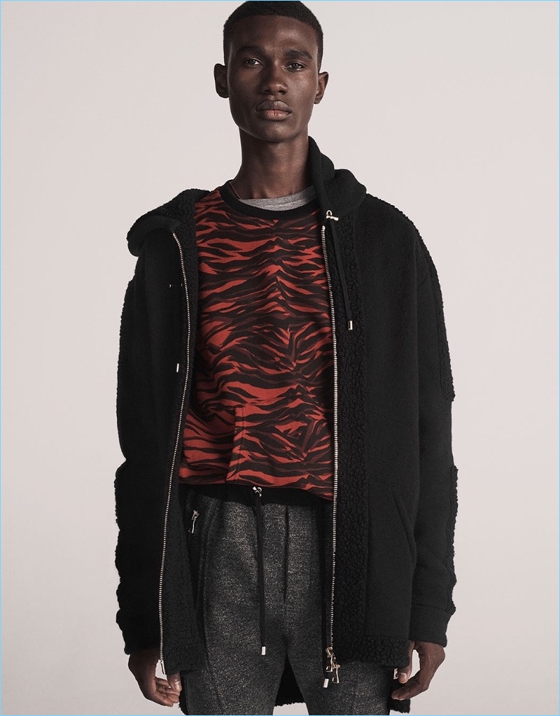 Making a case for black and red, Jean-Luc Harderwijk wears a Balmain loop-back jersey-trimmed hooded sweatshirt and buttoned-shoulder crew-neck sweater. His look is complete with a Balmain logo-print cotton t-shirt and drawstring wool-jersey track pants.